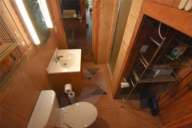 bathroom with toilet, tile walls, vanity, tile patterned floors, and a stall shower