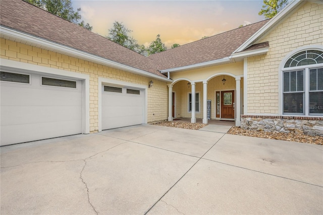 exterior space featuring driveway, a shingled roof, and an attached garage