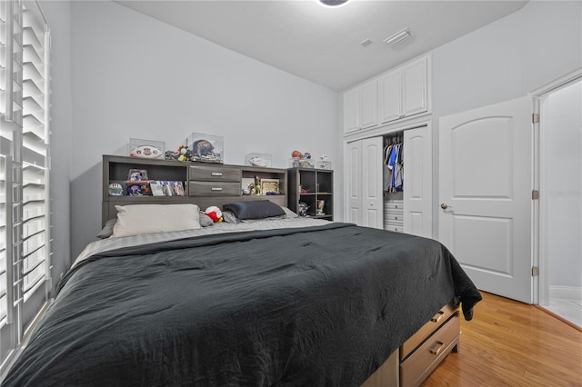 bedroom with a closet, light wood-type flooring, and visible vents