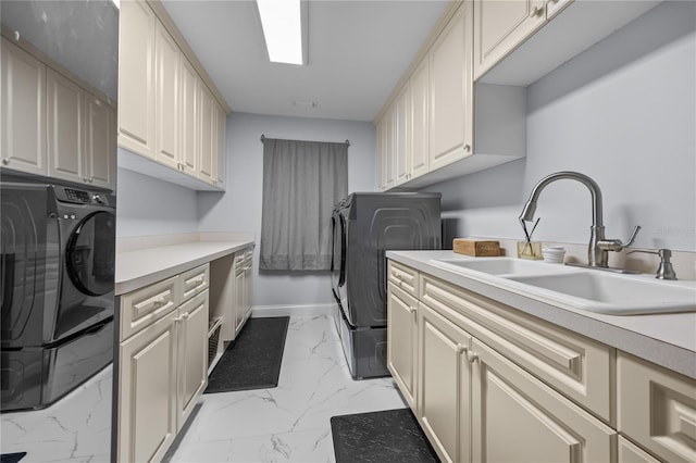 clothes washing area featuring separate washer and dryer, a sink, baseboards, marble finish floor, and cabinet space