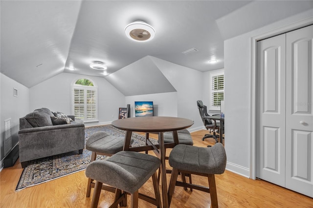 interior space with lofted ceiling, baseboards, visible vents, and light wood finished floors