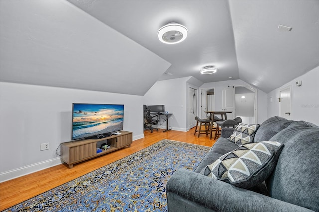 living room featuring lofted ceiling, baseboards, and wood finished floors