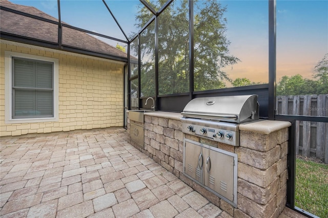 view of patio / terrace with an outdoor kitchen, glass enclosure, a grill, fence, and a sink