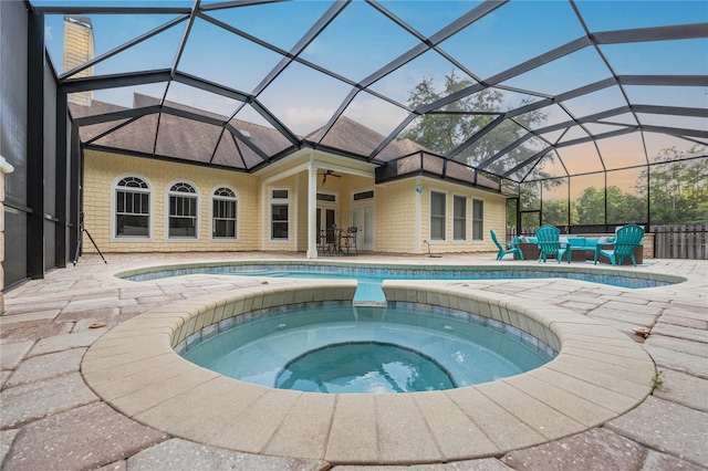 outdoor pool with ceiling fan, an in ground hot tub, a patio area, and glass enclosure