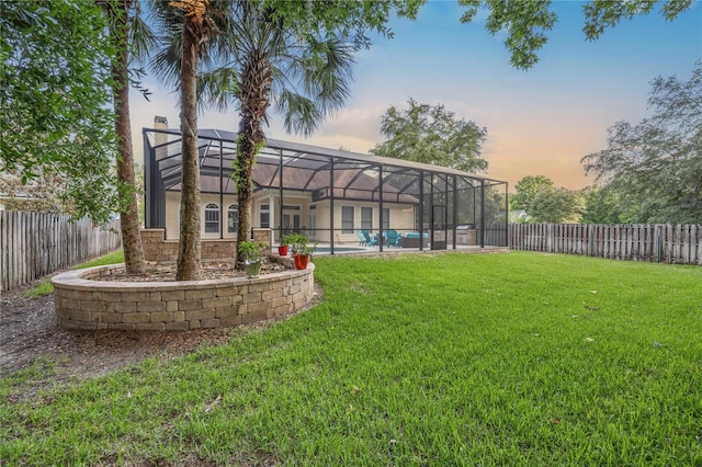 yard at dusk with a lanai, a fenced backyard, and a fenced in pool