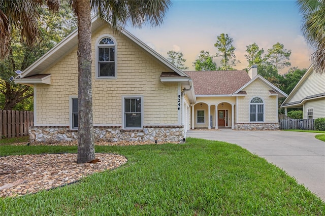 view of front facade featuring a yard, driveway, fence, and a chimney