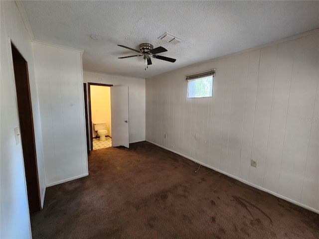 unfurnished bedroom with a ceiling fan, dark colored carpet, visible vents, and a textured ceiling