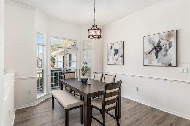 dining room featuring a notable chandelier, baseboards, ornamental molding, and wood finished floors