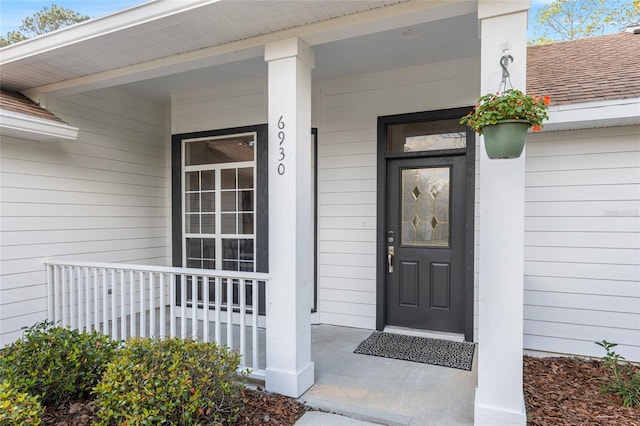 property entrance featuring covered porch and roof with shingles