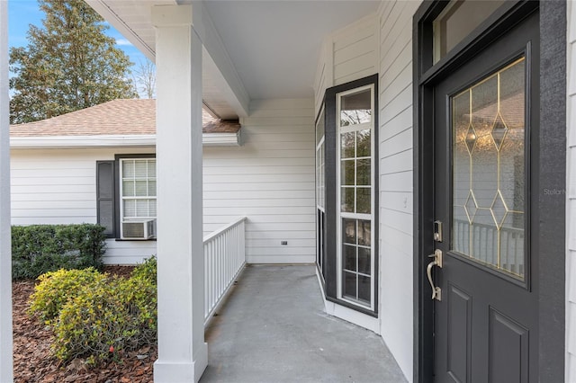 entrance to property with a porch and roof with shingles