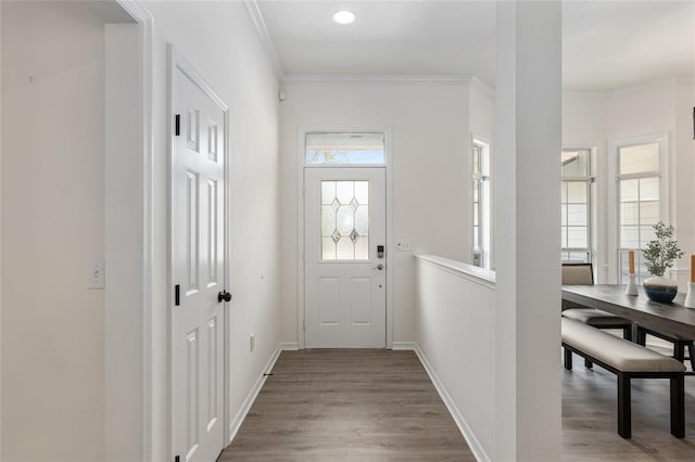 doorway to outside featuring baseboards, ornamental molding, and wood finished floors