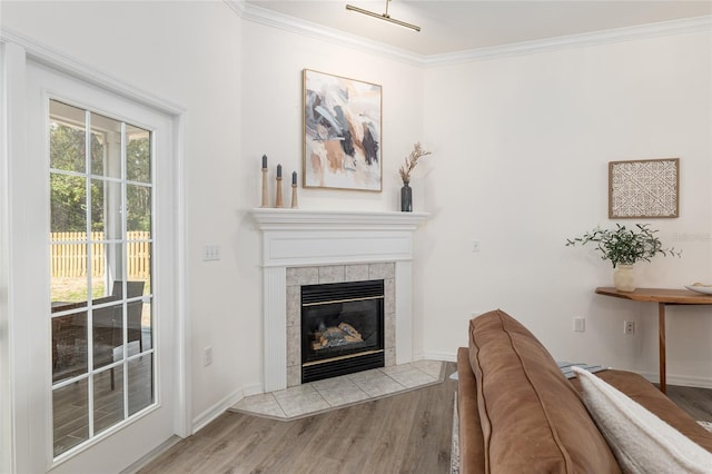 unfurnished living room featuring ornamental molding, a tiled fireplace, wood finished floors, and baseboards