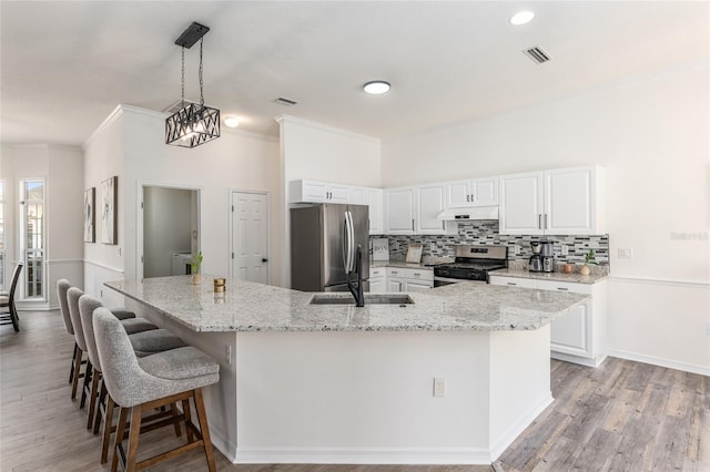 kitchen featuring visible vents, white cabinets, decorative backsplash, stainless steel appliances, and a sink