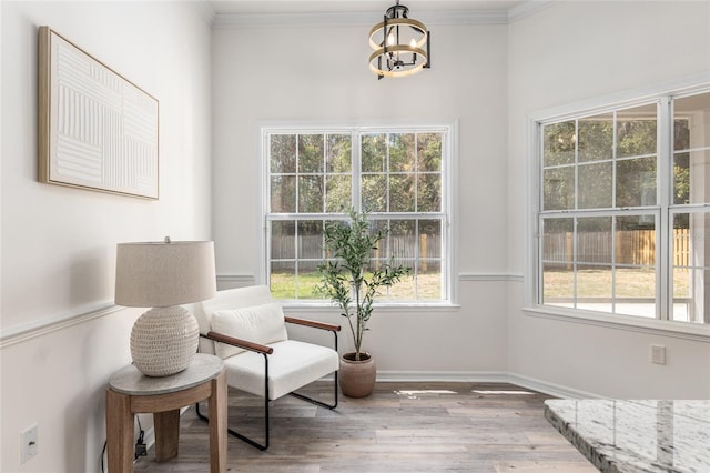 living area featuring ornamental molding, plenty of natural light, an inviting chandelier, and wood finished floors