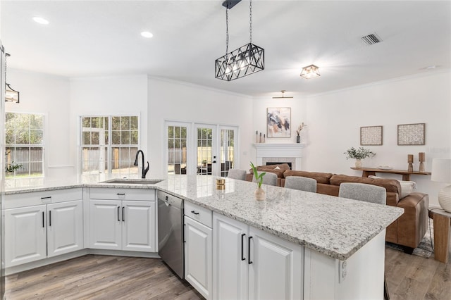 kitchen featuring stainless steel dishwasher, a fireplace, open floor plan, and a sink