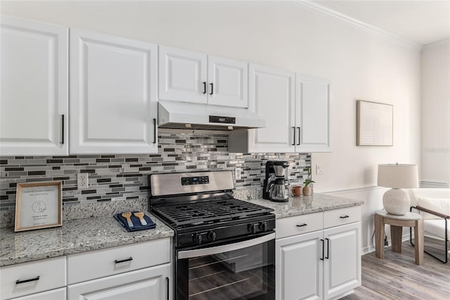 kitchen with stainless steel gas range oven, decorative backsplash, crown molding, under cabinet range hood, and white cabinetry