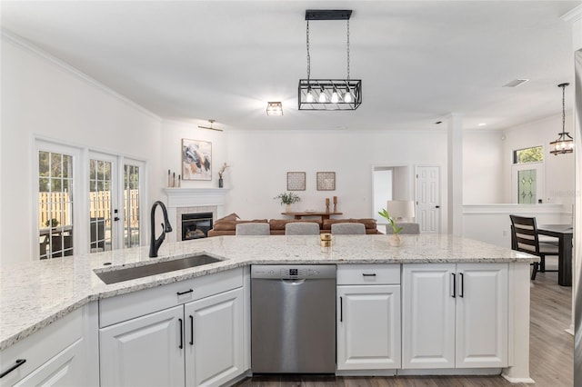 kitchen featuring pendant lighting, a fireplace, white cabinets, a sink, and dishwasher