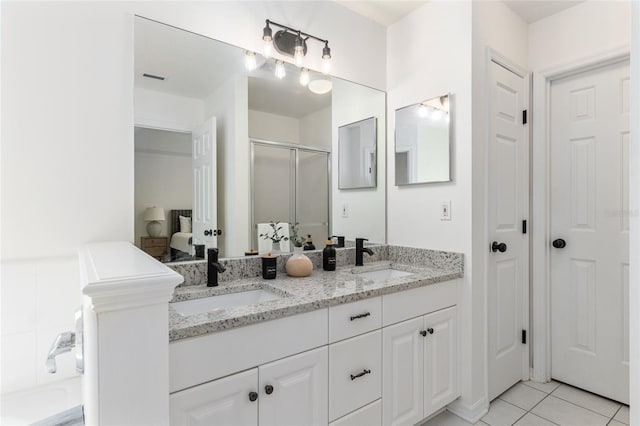 full bathroom with double vanity, a stall shower, a sink, and tile patterned floors