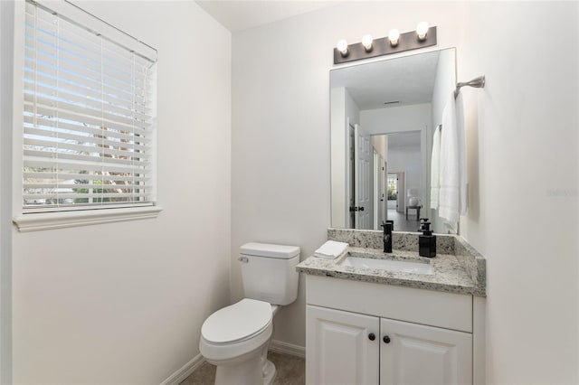 half bath featuring baseboards, vanity, and toilet