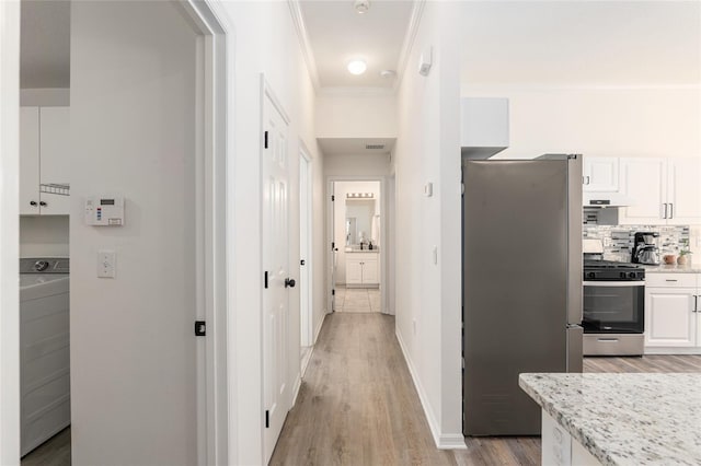 hall featuring baseboards, washer / clothes dryer, light wood-style flooring, and crown molding