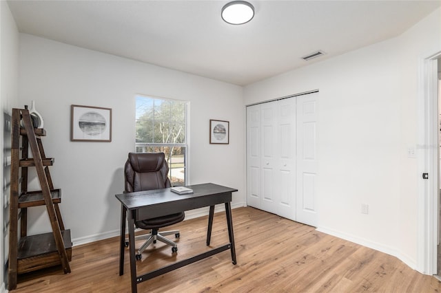 home office featuring light wood finished floors, visible vents, and baseboards