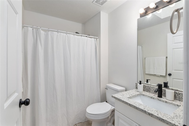 bathroom with toilet, vanity, and visible vents