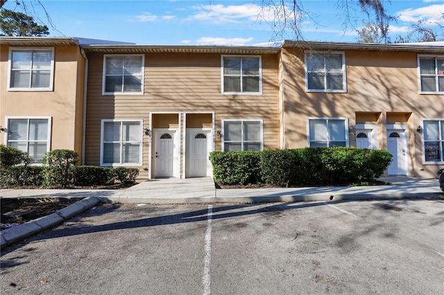 townhome / multi-family property with uncovered parking and stucco siding