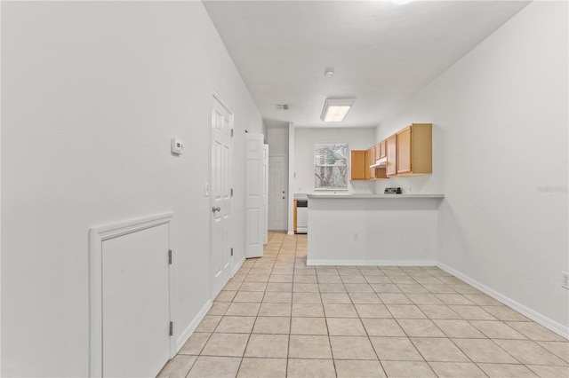 kitchen with light countertops, light tile patterned flooring, a peninsula, under cabinet range hood, and baseboards