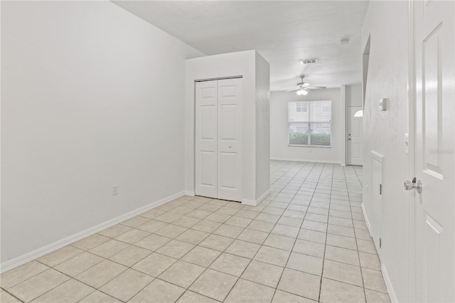 empty room with a ceiling fan, visible vents, baseboards, and light tile patterned floors