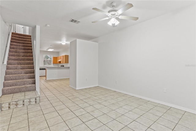 unfurnished living room with light tile patterned flooring, visible vents, baseboards, a ceiling fan, and stairway