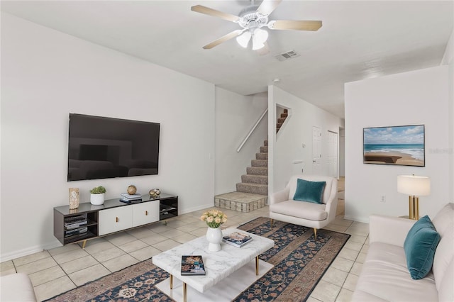 living room with ceiling fan, tile patterned flooring, visible vents, baseboards, and stairway