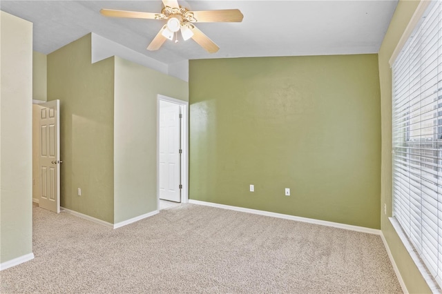 empty room with ceiling fan, baseboards, vaulted ceiling, and carpet flooring