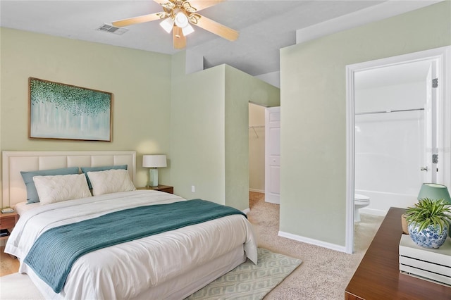 bedroom featuring baseboards, visible vents, ensuite bath, a walk in closet, and carpet flooring