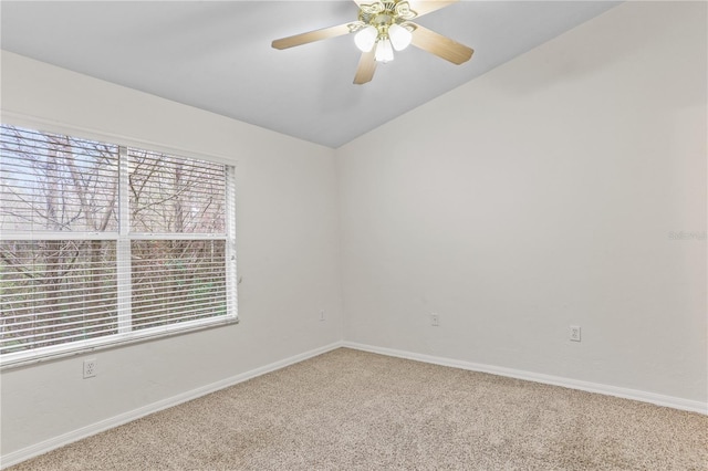 carpeted empty room featuring vaulted ceiling, baseboards, and ceiling fan