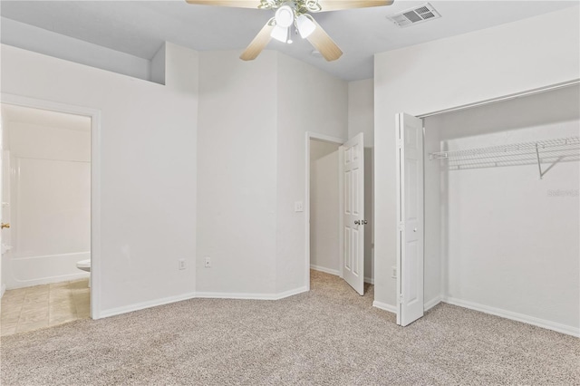 unfurnished bedroom featuring a closet, visible vents, ensuite bathroom, light carpet, and ceiling fan