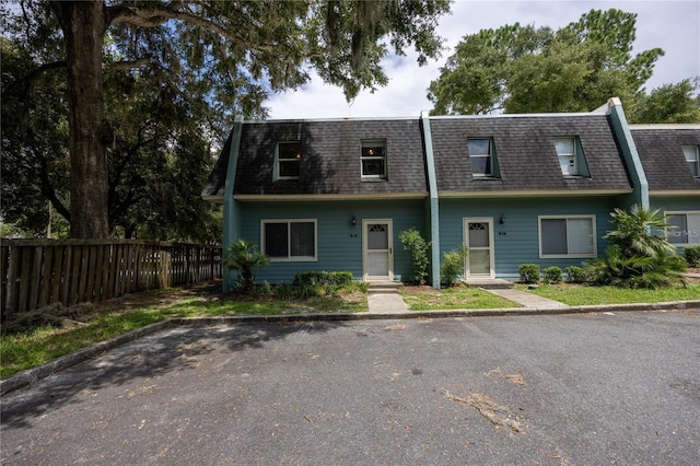 townhome / multi-family property featuring entry steps, roof with shingles, fence, and mansard roof