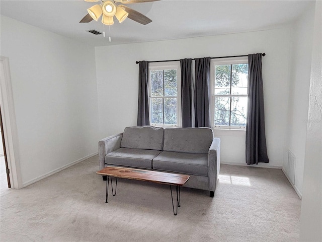 living area with ceiling fan, visible vents, and light colored carpet