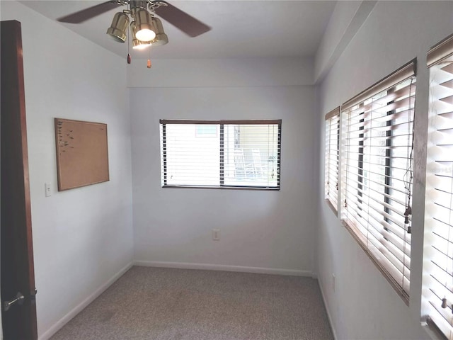 empty room with carpet floors, a ceiling fan, and baseboards