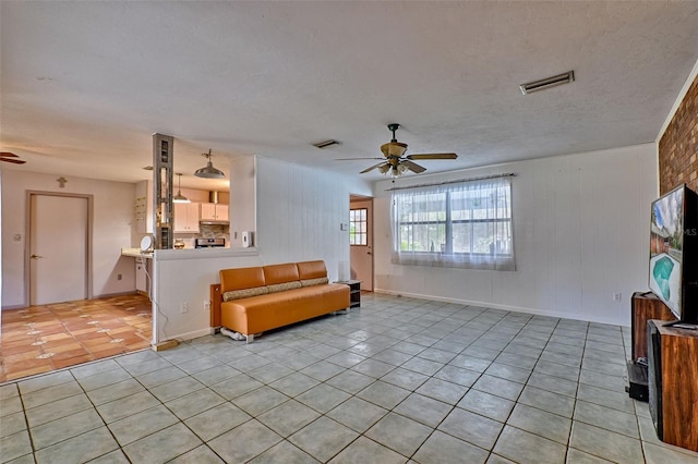 living room with a ceiling fan, visible vents, and light tile patterned floors