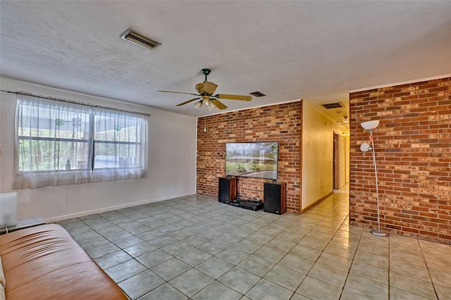 unfurnished living room with light tile patterned floors, brick wall, visible vents, and a textured ceiling