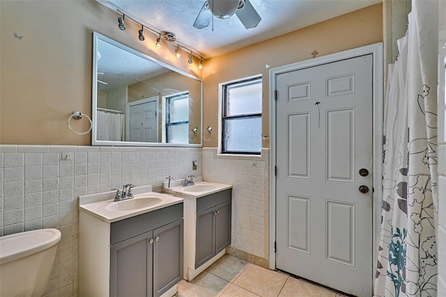 bathroom with toilet, a ceiling fan, tile walls, vanity, and tile patterned floors