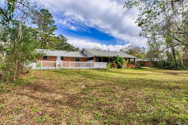 back of property with fence private yard, brick siding, and a yard