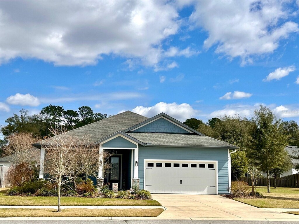 6657 SW Lugano Ct, Gainesville, FL 32608 - single story home with driveway, roof with shingles, an attached garage, and fence