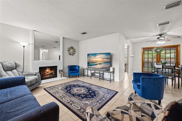 living room with a warm lit fireplace, visible vents, and light tile patterned flooring