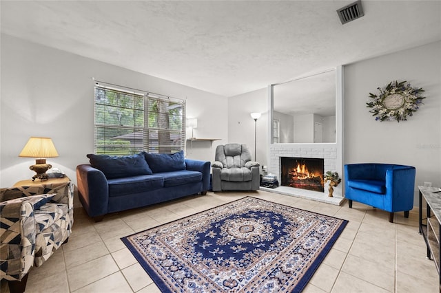 living room featuring visible vents, a fireplace, a textured ceiling, and light tile patterned floors