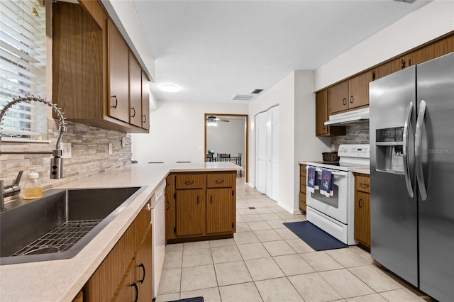 kitchen with under cabinet range hood, a peninsula, white appliances, a sink, and light countertops