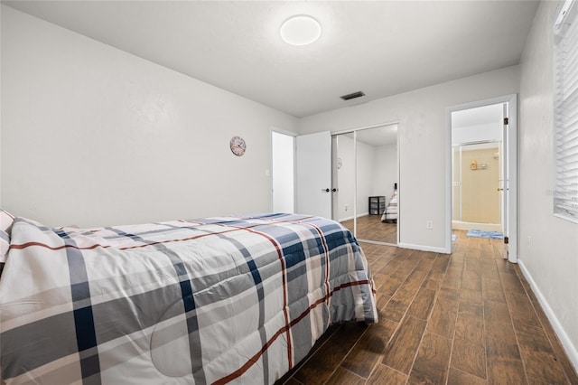 bedroom featuring baseboards, visible vents, dark wood finished floors, and a closet