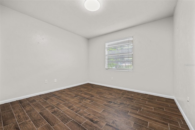 unfurnished room with dark wood-type flooring and baseboards