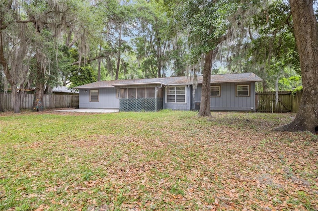 rear view of property featuring a sunroom, a fenced backyard, and a yard