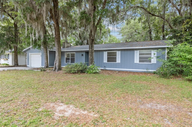 single story home with an attached garage, driveway, a chimney, and a front lawn